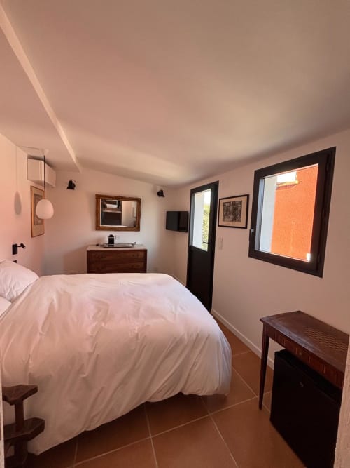 Chambre lumineuse dans l'appartement d'Erbalunga avec literie blanche, mobilier en bois foncé et vue sur la mer
