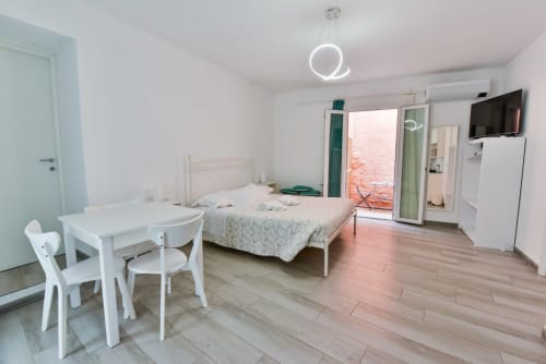 Luminoso monolocale a Varigotti con letto, tavolo da pranzo, TV, balcone in cotto, lampada a sospensione circolare moderna, aria