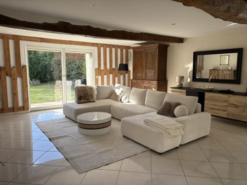 Salon moderne au Le Jardin d'Elusa B&B à Eauze avec canapé sectionnel crème, poutres apparentes et vue sur le jardin