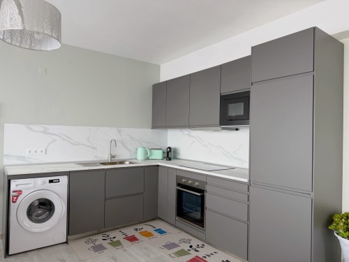 Modern kitchen with gray cabinetry, marble backsplash, stove, oven, and washing machine at Isabella's House villa in Ribeira