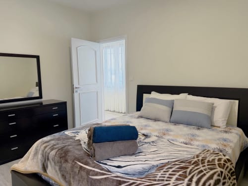 Bedroom at Isabella's House villa in Ribeira Brava with black furniture, queen bed, and folded towels
