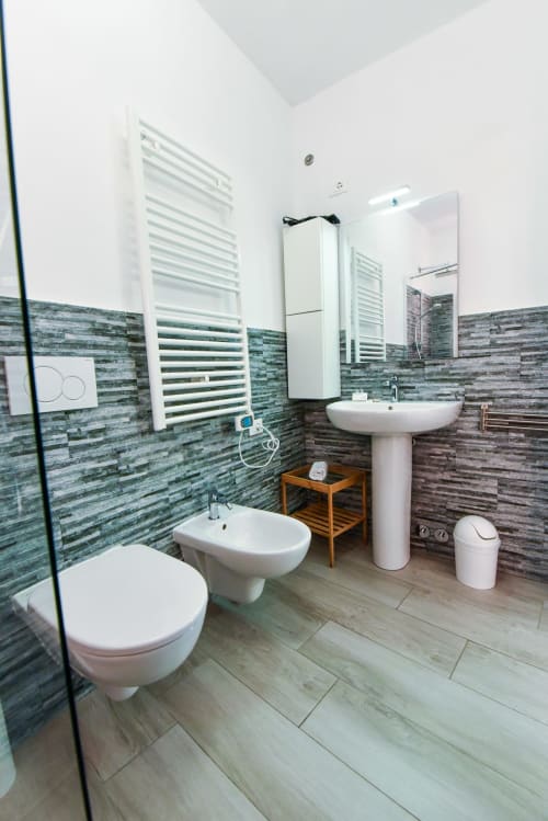 Moderno bagno nell'appartamento di Varigotti con piastrelle verdi, lavabo su colonna, bidet, wc e scaldasalviette