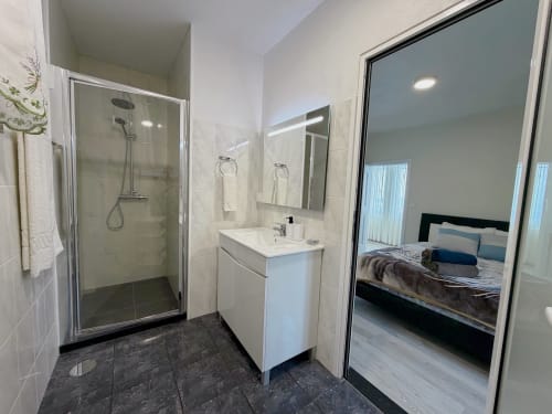 Banheiro moderno do hotel Check Madeira com box walk-in, cuba branca e vista para o quarto pela porta aberta