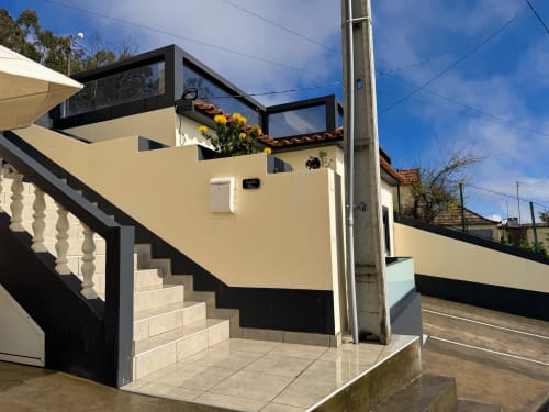 Entrada moderna do hotel Check Madeira em Ribeira Brava com fachada amarela, detalhes em preto e jardineiras com flores