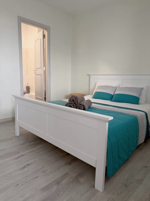 Quarto moderno do hotel Check Madeira em Ribeira Brava com cama branca, roupa de cama azul-turquesa e casa de banho privativa