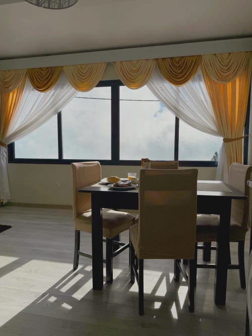 Elegante sala de jantar do hotel Check Madeira em Ribeira Brava com mesa preta, cadeiras estofadas e cortinas douradas