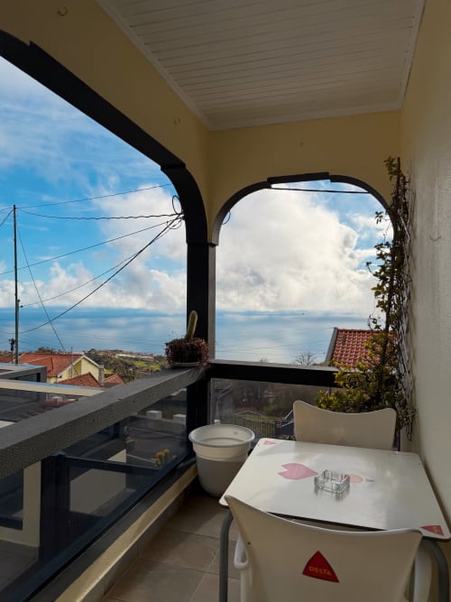 Varanda do hotel Check Madeira em Ribeira Brava com vista para o mar, mesa, cadeiras e vistas costeiras