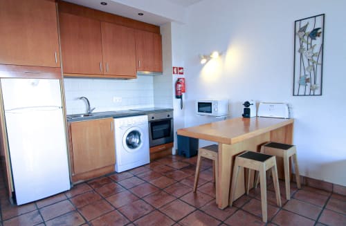 Cozinha moderna e área de refeições no apartamento Villa Alegria em Zonas Mágicas, Lagos com armários em madeira, eletrodomésticos e acabamentos de madeira