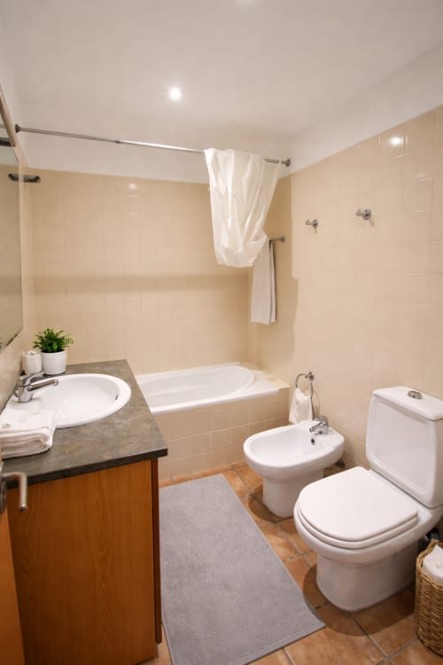 Banheiro moderno da Villa Alegria em Zonas Mágicas Lagos com pia, vaso sanitário, bidê, banheira e azulejos brancos