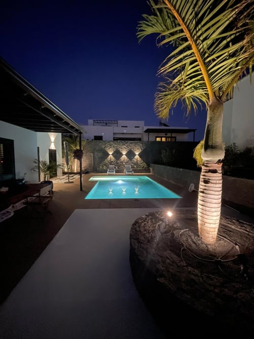 Piscina iluminada y palmera en la villa Sports and Culture Nest en Playa Blanca, Lanzarote, al atardecer