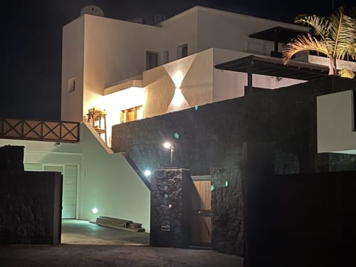 Villa moderna con fachada blanca y muros de piedra negra iluminada de noche en Playa Blanca, Lanzarote