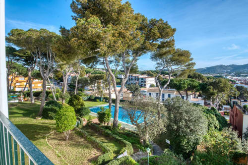 Jardí d'hotel a Palafrugell amb arbres mediterranis, piscina i vistes al mar