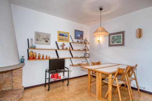 Menjador de Finques Garcia Enrich, Palafrugell amb taula de fusta, cadires, estanteria i xemeneia