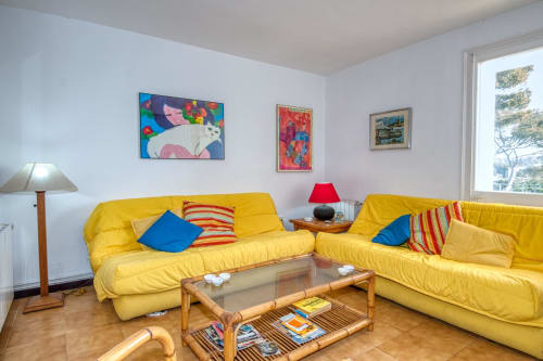 Sofàs groc brillant a la sala d'estar de Finques Garcia Enrich, Palafrugell, amb coixins acolorits i obres d'art modern