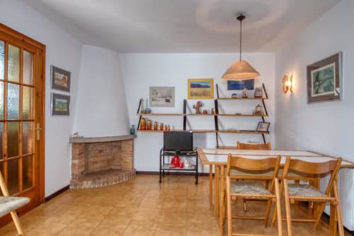 Espaïos sala d'estar de la casa rural de Palafrugell amb mobles de fusta, llar de foc, estanteries i sòl de teula