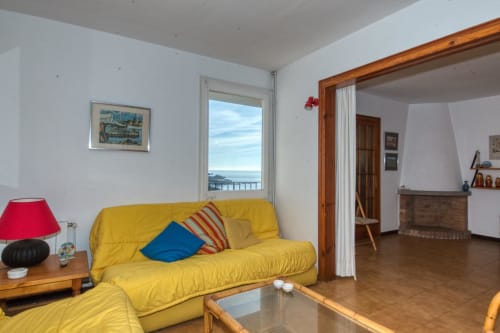 Sala clara amb sofà groc amb vistes al mar a Finques Garcia Enrich, Palafrugell