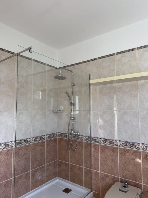 Moderno baño con azulejos de mármol y ducha de efecto lluvia en la villa Kamalahouse, Corralejo