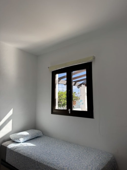 Dormitorio luminoso con cama doble y ventana de marco negro con vista al jardín en villa Kamalahouse, Corralejo
