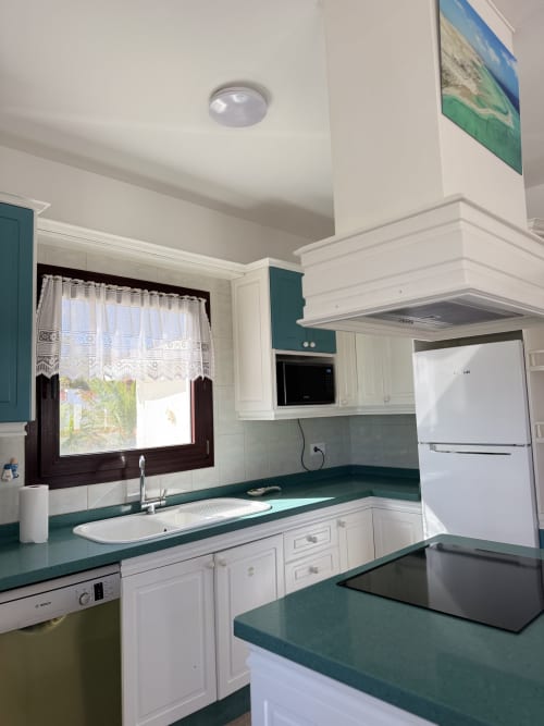 Cocina moderna con encimeras en tonos azules, gabinetes blancos y electrodomésticos de acero inoxidable en la villa Kamalahouse de Corralejo