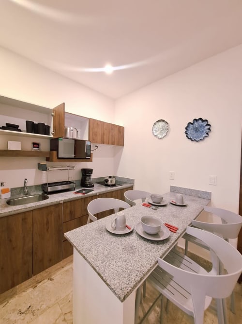 Modern kitchen and dining area in Itzamná Suite Deluxe, Playa del Carmen with granite counters and white chairs