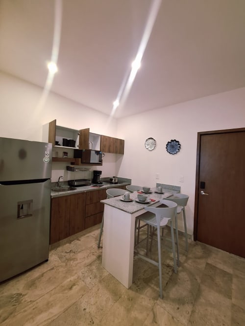Modern kitchen with dining area in Itzamna Suite Deluxe, Playa del Carmen apartment featuring stainless steel appliances and