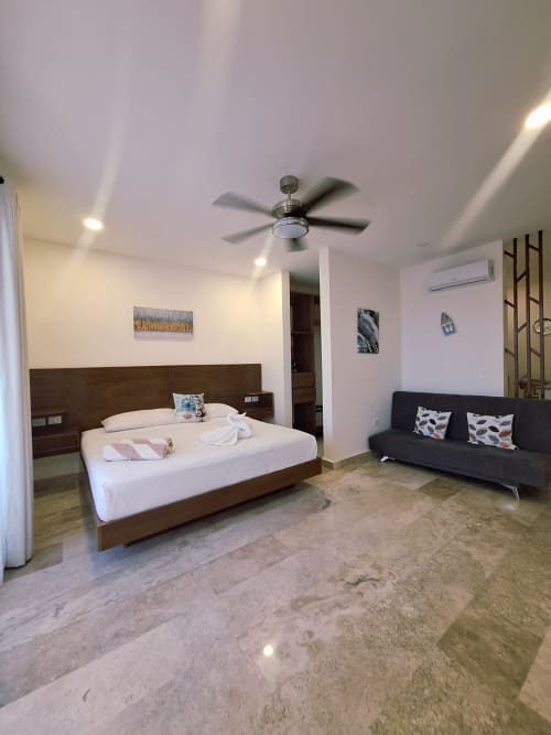 Suite spacieuse à Itzamná Rentals à Playa del Carmen avec lit king, canapé noir, ventilateur et équipements modernes