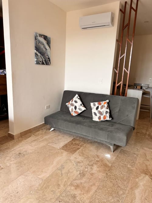Gray sofa with leaf-patterned pillows in Itzamná Suite Deluxe at Playa del Carmen apartment rental