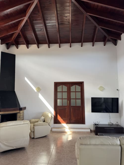 Moderna sala de estar con vigas de madera vista, chimenea y puertas hacia el jardín en Kamalahouse, Corralejo