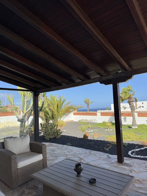 Terraza de la villa con pérgola, vista al jardín, mar al fondo, palmeras y cactus en Kamalahouse, Corralejo