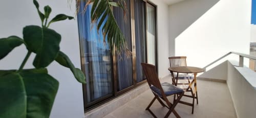 Spacious balcony at Itzamna Suite Deluxe in Playa del Carmen with wooden chairs, potted plants, and city views