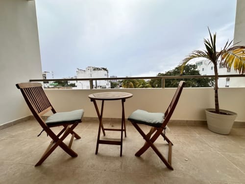Balcony seating area at Itzamna Rentals Playa del Carmen with wooden chairs, table, and city views