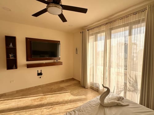 Itzamná Suite Deluxe bedroom in Playa del Carmen with wall-mounted TV, ceiling fan, and terrace view