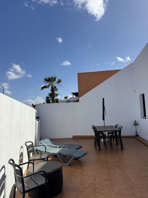Terraza en la azotea de Kamalahouse en Corralejo con tumbonas, mesa de comedor y vistas a palmeras