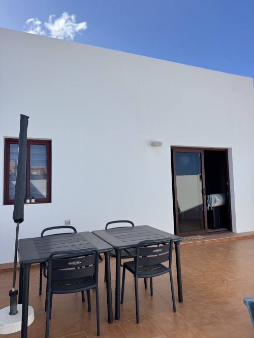 Terraza moderna de Kamalahouse en Corralejo con muebles de comedor negro y vistas al mar