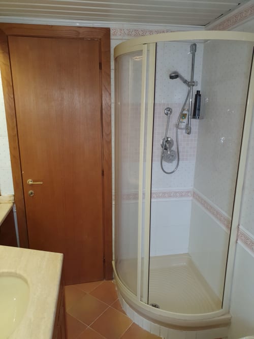 Bagno moderno con doccia angolare curva, piastrelle bianche e rubinetteria presso la Myob Altipiani di Arcinazzo Residence