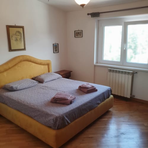 Camera luminosa al Residence Altipiani di Arcinazzo a Roma con letto giallo, biancheria grigia e comfort moderni