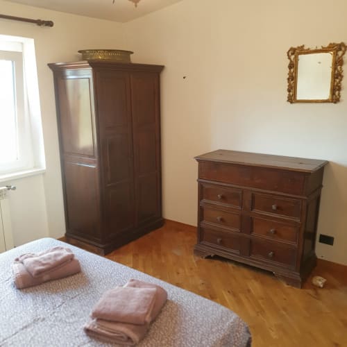 Spaziosa camera da letto presso la Residenza Altipiani di Arcinazzo, Roma, arredata con mobili in legno, cassettiera, armadio e letti gemelli con biancheria rosa