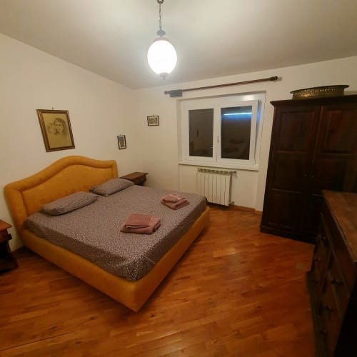 Spaziosa camera da letto presso Altipiani di Arcinazzo Residence, Roma con letto arancione, pavimenti in legno, armadio scuro e arredamento moderno