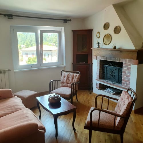 Accogliente soggiorno con camino, pavimenti in legno e vista sulle montagne presso Altipiani di Arcinazzo Residence, Roma