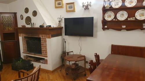 Elegante soggiorno ad Arcinazzo con camino, TV a schermo piatto, mobili in legno e piatti decorativi