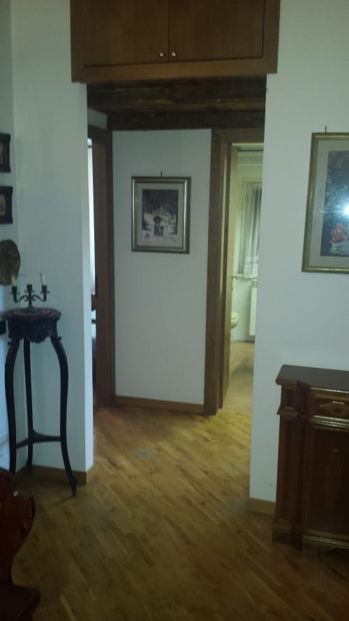 Elegante corridoio di appartamento a Roma con porte in legno, opere d'arte incorniciate, arredamento in legno scuro e pavimenti in legno massello