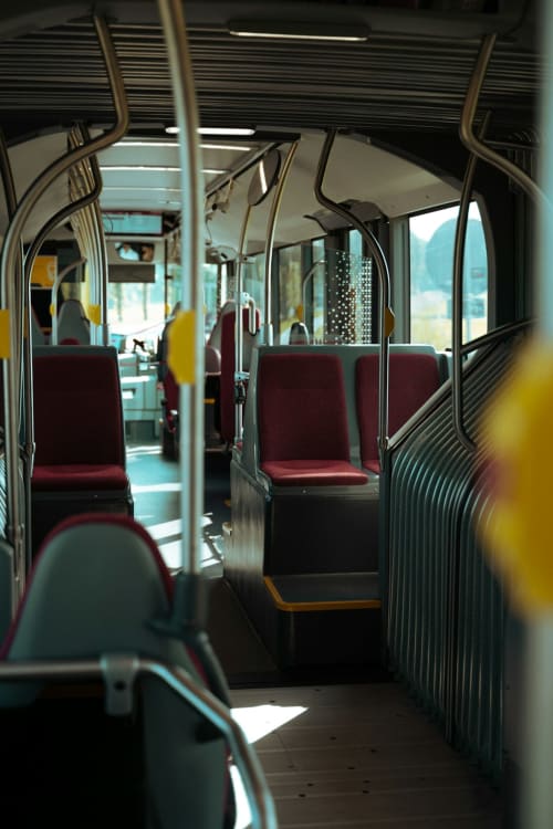 Innenraum eines Linienbusses mit burgunderroten Sitzen und metallenen Haltegriffen in der Nähe von La Sage, CH