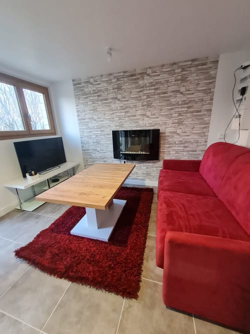 Séjour moderne avec canapé rouge, cheminée, table en bois et vue sur les montagnes à Ô Panora'Gîte à Boëge