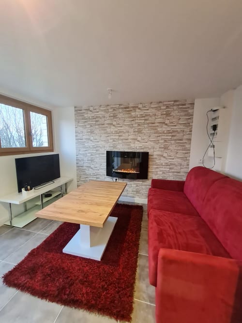 Séjour moderne à Ô Panora'Gîte à Boëge avec canapé rouge, cheminée et table en bois