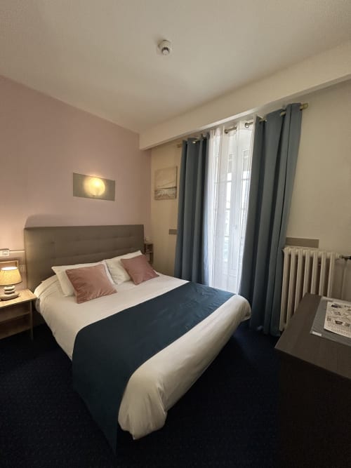 Chambre double de l'Hôtel Le Centre aux Herbiers avec lit queen, vue sur la ville, TV, bureau et mobilier moderne