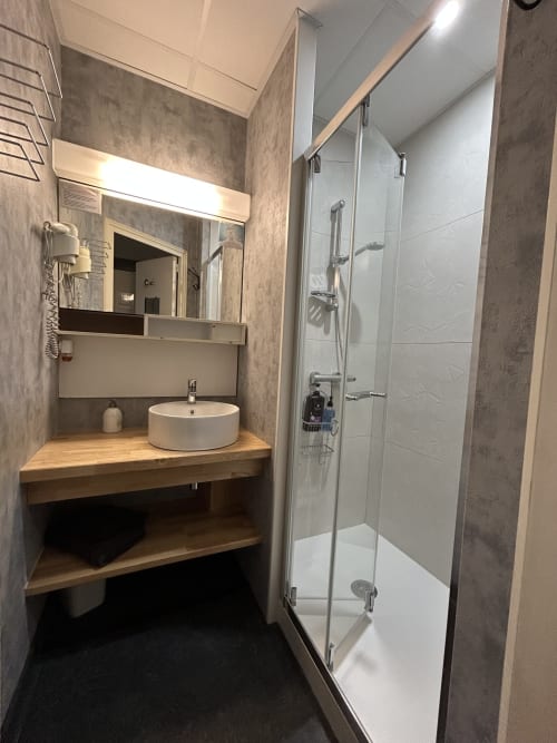 Modern bathroom at Hotel Le Centre with round sink, wooden vanity, and walk-in shower