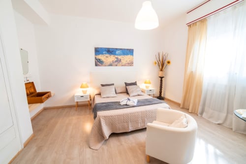 Spacious bedroom at Belvedere del Lago with queen bed, white pendant light, garden view, and wooden flooring in Montefiascone