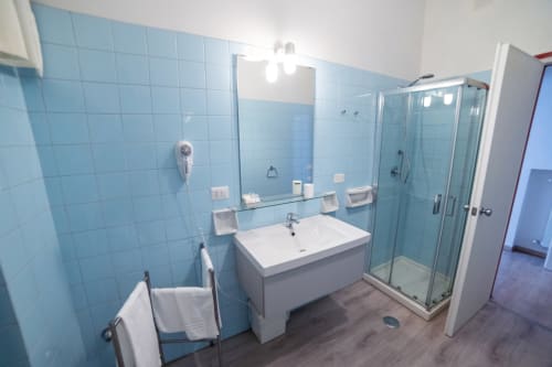 Modern bathroom with light blue tiles, white sink vanity, glass shower enclosure at Belvedere del Lago, Montefiascone