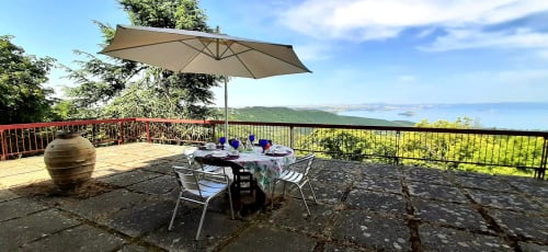 Terrace dining area at Belvedere del Lago with lake view, umbrella, and garden seating in Montefiascone