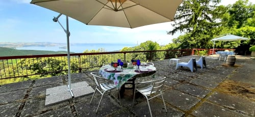 Outdoor terrace at Belvedere del Lago in Montefiascone with lake views, dining table under umbrella, and garden seating area